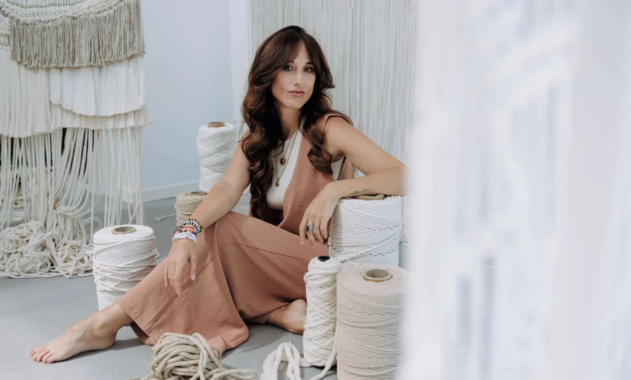 Sara sentada en su estudio, rodeada de fibras naturales, al inicio del proceso creativo de un tapiz personalizado